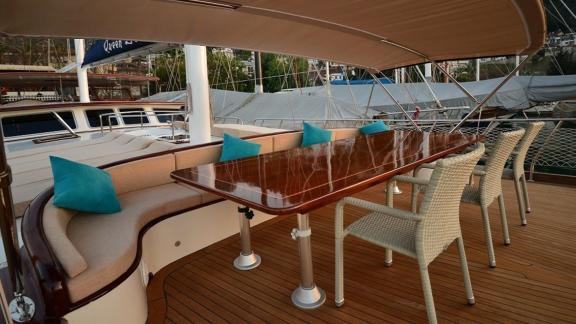 Shaded dining area on the deck of the Queen Lila, with comfortable seating and an elegant table.