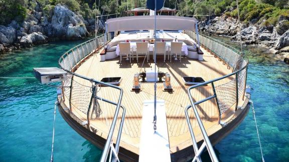 View of the spacious deck of the Queen Lila, surrounded by clear water and rocky shores.