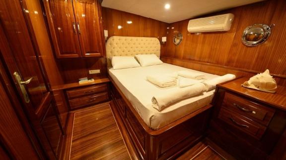 Comfortable guest cabin on the Queen Lila, with stylish wood panelling and cosy bed.