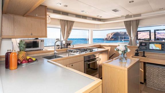 Modern kitchen with a fruit bowl and sea view through large windows.