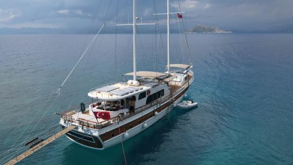 The elegant gulet Queen of RTT is anchored off the coast of Fethiye in the calm turquoise waters.