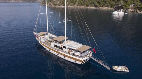 The gulet Queen of RTT is moored in the calm waters of Fethiye, accompanied by a dinghy, ready for adventure.