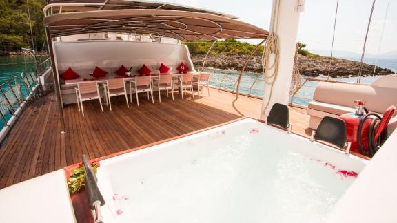 The outdoor area of the Gulet Queen of RTT offers a relaxing whirlpool and a cosy dining area with red cushions.