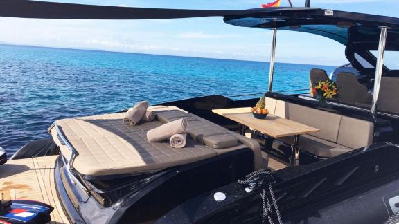 Yacht My Way liegt vor Ibiza mit Sonnenbereich und Esstisch am Heck.