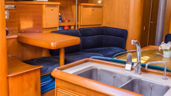 Гостиная и кухня на парусной яхте Conformista создают теплую атмосферу с деревянной мебелью.