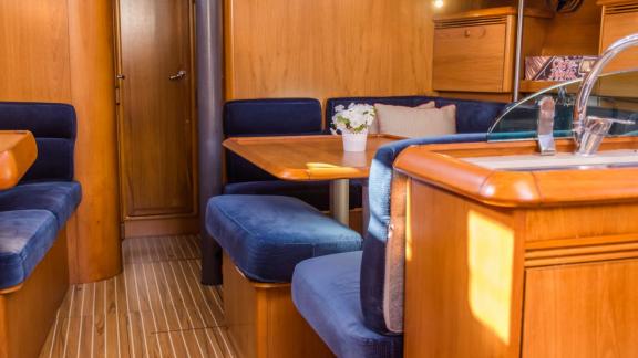 Уютная обеденная зона в интерьере парусной яхты Conformista украшена синими подушками.