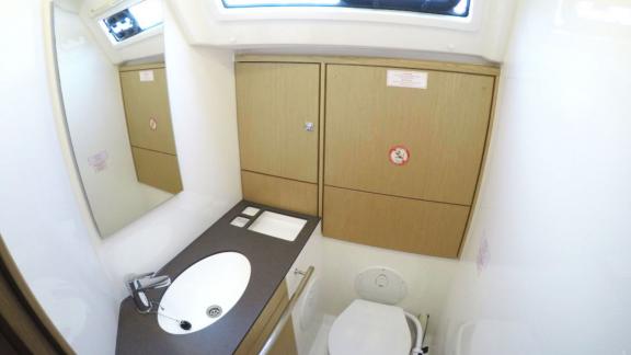 The bathroom of the yacht Rama is equipped with a simple sink, a large mirror, and storage cabinets.