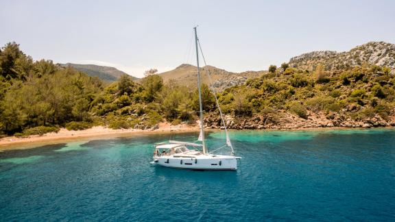 Sailing yacht Sam's Wind anchored in a tranquil bay surrounded by lush greenery.