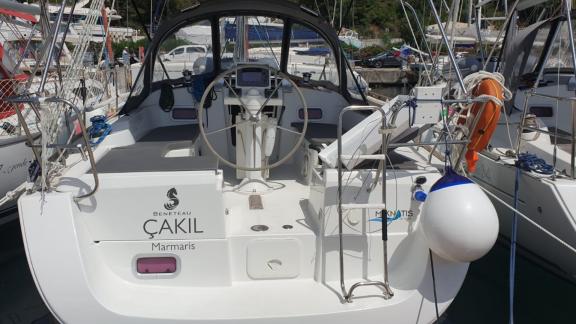 The cockpit of the sailing yacht Çakıl, featuring the helm and seating areas, is visible in the harbor.