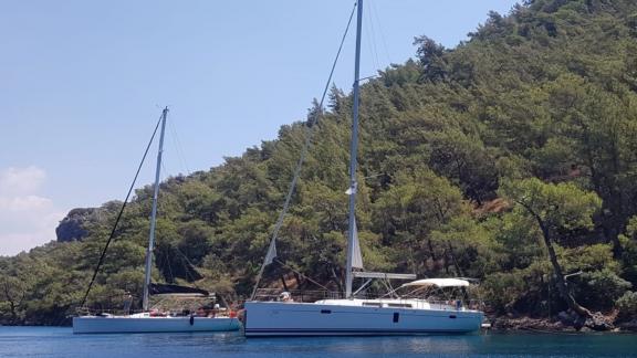 Fox sailing yacht anchored in a tranquil bay surrounded by trees, offering a peaceful setting.