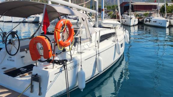 The aft deck of Lima sailing yacht with lifebuoys and equipment docked in the harbor.