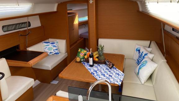 The saloon of the Yerdeniz sailing yacht features a stylish dining table, marine-themed cushions, and a fruit basket.