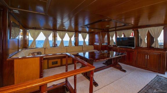 Cosy interior of the gulet Vesta 1 Sevil with comfortable seating area and TV, surrounded by windows with sea views.