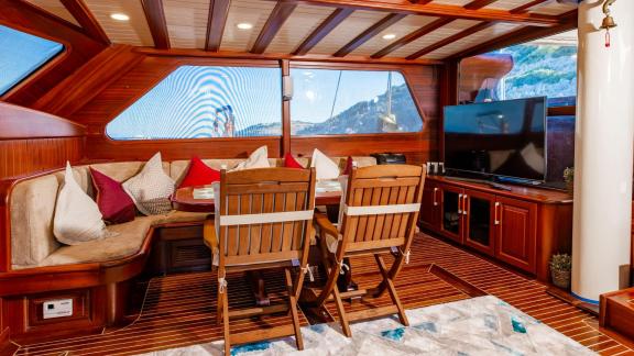 Stilvolles Wohnzimmer der 24-Meter-Gulet Sani Kaptan 2 mit gemütlicher Sitzecke und TV, ideal für Entspannung in Bodrum,