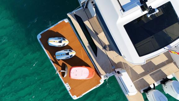 The aft platform of motor yacht Bali features sea scooters and paddleboards for water sports.