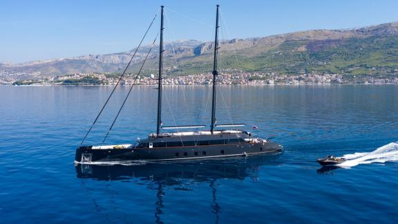 Among Split yacht charter options the 6 cabin 12 guest Scorpios motorsailer cruising at sea with tender.