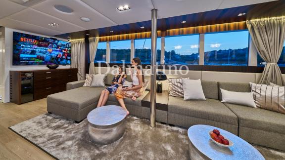 Gemütlicher Wohnbereich mit Sofas, großem Fernseher und Panoramafenstern auf der Dalmatino-Yacht.