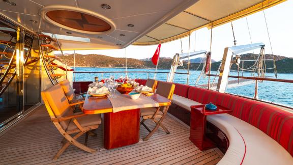 In Göcek gulet charter option Serenity 86 aft deck with dining table seating area and sea view offering relaxing space v