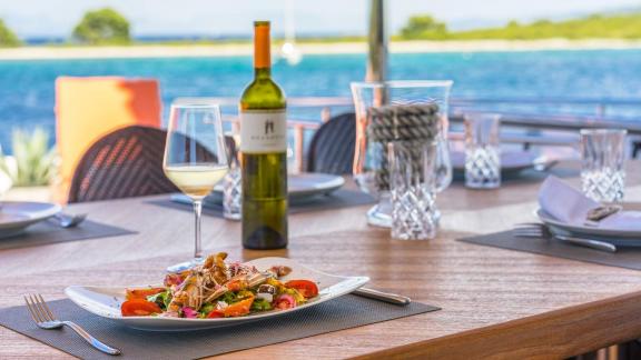 Hochwertige Mahlzeit und Wein auf einem schön gedeckten Tisch an Bord der Motoryacht Seventh Sense in Rogoznica.