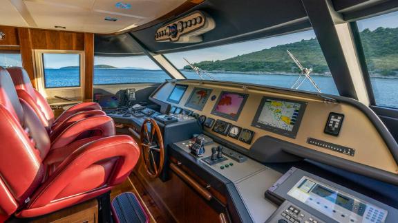 Hochtechnologische Steuerbrücke mit rotem Kapitänssitz und beeindruckendem Meerblick auf der Motoryacht Seventh Sense in