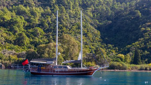 Die 24 Meter Gulet Yüce Bey ankert friedlich vor einer üppig grünen Küstenlandschaft in Marmaris, Türkei.