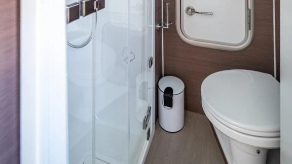 Functional bathroom with a shower, toilet, and elegant wood details on the Bali Catamaran Signature Concept.