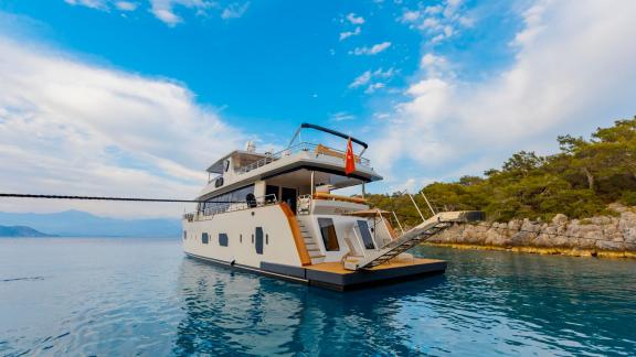 Die Yacht Simay M, vor Anker in türkisfarbenen Gewässern, elegant vom Heck aus fotografiert.