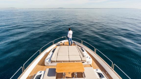 Wide cushions and table on bow deck of Sirena 64 yacht offer scenic relaxation.