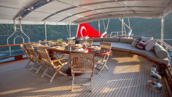 A stylish dining area on a gulet with the Turkish flag in the background, set for dinner.