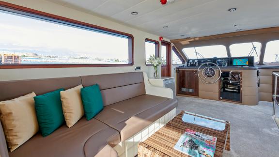 Cozy lounge area next to the helm of the motor yacht Wide Liberty with panoramic views.