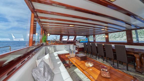 Interior of a sailing yacht with comfortable lounge, white sofas, wooden tables and large windows offering a view of the