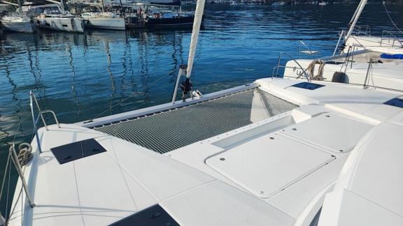 The foredeck of the Reina 1 catamaran, the yacht is docked in the marina alongside other boats.