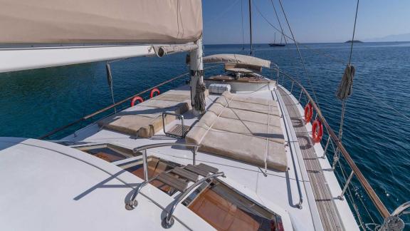 The sun deck of a Bodrum gulet with 5 cabins, equipped with comfortable sunbathing areas, while it anchors in the calm,