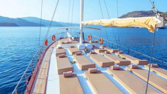 The spacious sun deck of Gulet Rüya with numerous sunbeds and a stunning view of the sea.