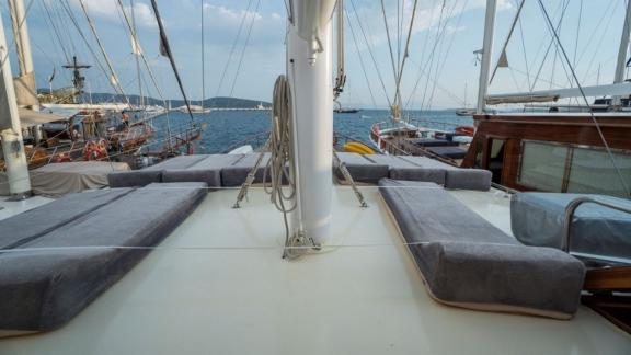 Spacious sun deck on the Gulet Optimist with comfortable loungers and a view of the harbor and sea.