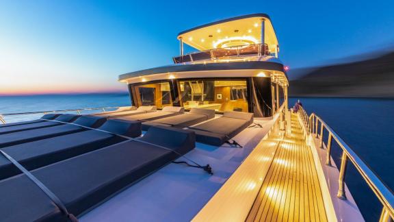 Elegant sunbathing area on the deck of Floki trawler yacht, illuminated in the evening.