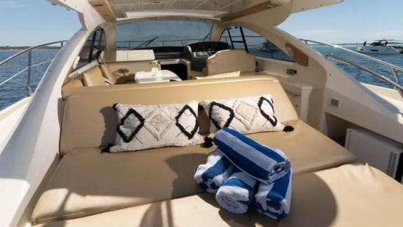 The aft deck of motor yacht Breathe features a relaxation area with cushions and towels.