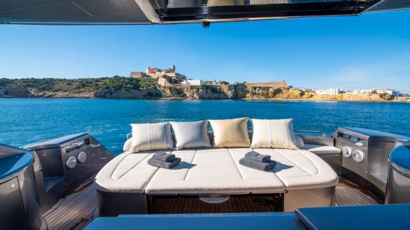 Am Heck der Yacht Optimum befindet sich eine gepolsterte Liegefläche. Dahinter liegt die Festung von Ibiza.