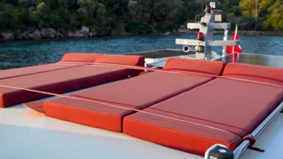 Spacious sunbathing area with red cushions on the upper deck of Barbaros 3 lobster yacht.