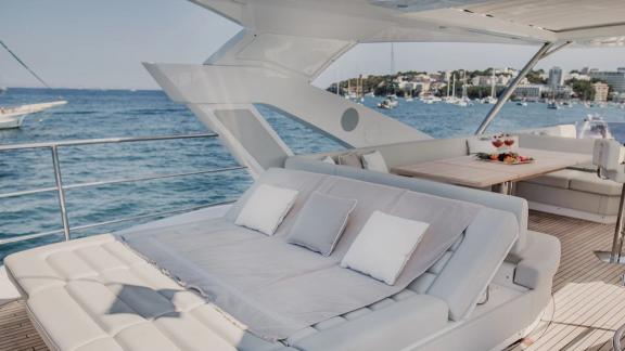 The flybridge of Lady M in Mallorca includes a sunbed and a rear table with drinks.