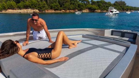A couple relaxes on the bow sunbeds of the yacht while anchored in turquoise waters.