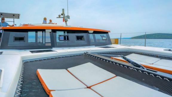 В Сплите на катамаране Orange зона отдыха на сетке и окна салона спереди.