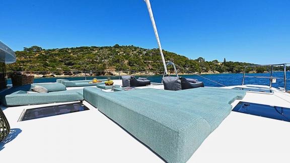 The foredeck of Ace of Hearts in Athens features large cushioned sunbeds and a scenic bay view.