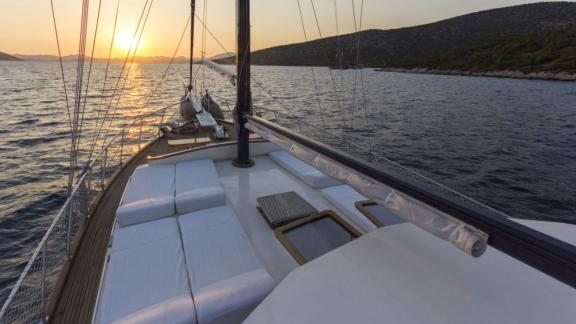 Segeldeck mit gepolsterten Sitzflächen und Sonnenuntergang im Hintergrund.