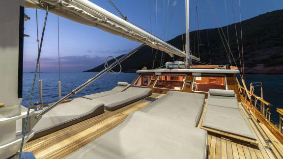 Spacious deck of a luxury sailing yacht with comfortable sunbeds at sunset, off the coast of Bodrum.