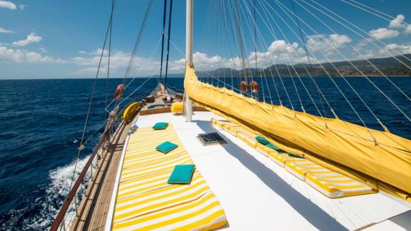 Das sonnige Deck der Bodrum-Gulet Flas VII mit gelben Polstern und Blick auf das weite Meer.