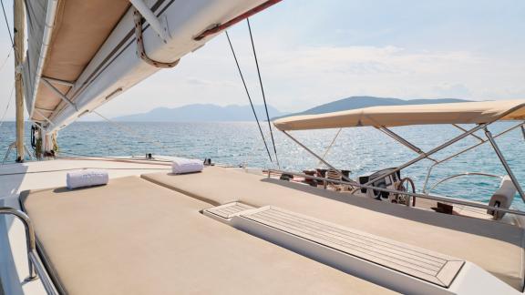 Großzügige Sonnenliegen auf dem vorderen Deck eines Katamarans mit Blick auf das Meer und die Berge im Hintergrund.