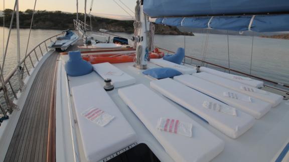 Sun loungers with towels on the deck, surrounded by calm water and rocky coast.