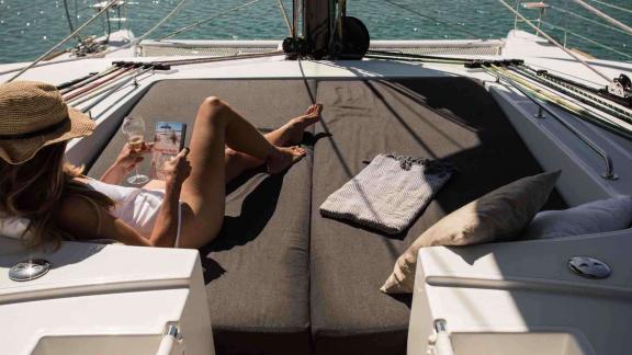 Woman lounging on the deck of Soleanis II, enjoying a glass of wine and reading a magazine