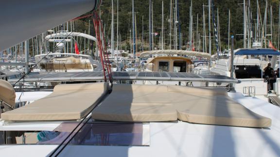 Beige sun pads on the roof of Catamaran Ayda1 with a view of the marina.